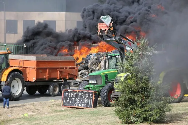French farmers gather in front of Lactalis' factory, Monday, July 27, 2015, in Laval, western France in order to protest against importation of foreign meat and milk products in France. The protests are a rejection of the government offer to back loans to the farmers and delay tax payments as part of a 600 million euro plan. Banner reads: “Same price for the milk for 15 years”. (Photo by David Vincent/AP Photo)