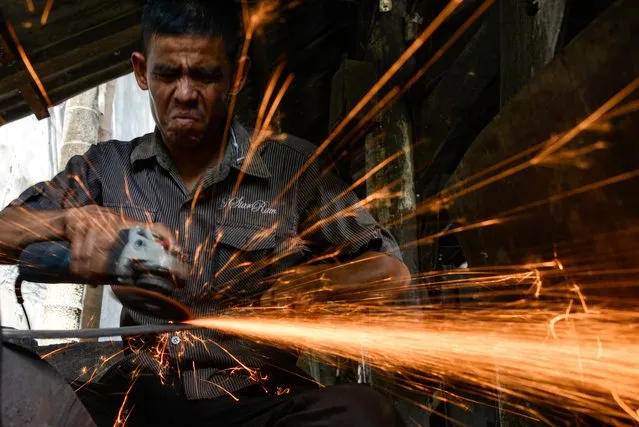 A blacksmith uses a grinder to make a knife at a traditional workshop in Darul Imarah, Aceh province on November 4, 2019. (Photo by Chaideer Mahyuddin/AFP Photo)