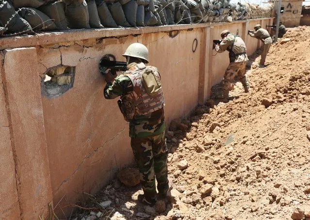 Kurdish peshmerga fighters take their positions behind a wall on the front line with militants from the al-Qaida-inspired Islamic State in Iraq and the Levant (ISIL), in Tuz Khormato, 100 kilometers (62 miles) south of the oil rich province of Kirkuk, northern Iraq, Wednesday, June 25, 2014. (Photo by Hussein Malla/AP Photo)