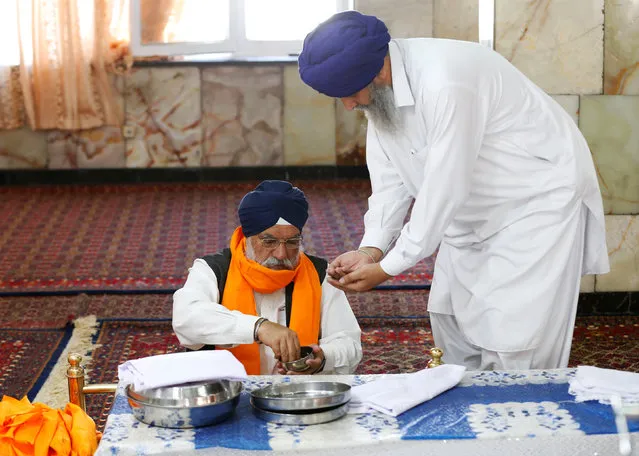 An Afghan Sikh (R) receives karah prasad, a sweet pudding offering given out to a congregation at the end of prayer, inside a Gurudwara, or a Sikh temple, during a religious ceremony in Kabul, Afghanistan June 8, 2016. (Photo by Mohammad Ismail/Reuters)