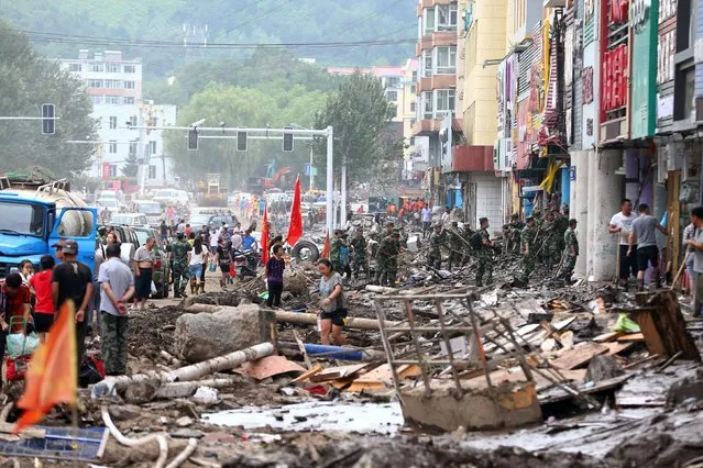 his photo taken on July 15, 2017 shows people cleaning up after flooding in Yongji, a county under the administration of the city of Jilin in northeast China' s Jilin province. Heavy rains caused flooding that left 18 people dead and another 18 missing around Jilin, with more than 110,000 evacuated when flooding hit the city on July 13 and 14. (Photo by AFP Photo/Stringer)