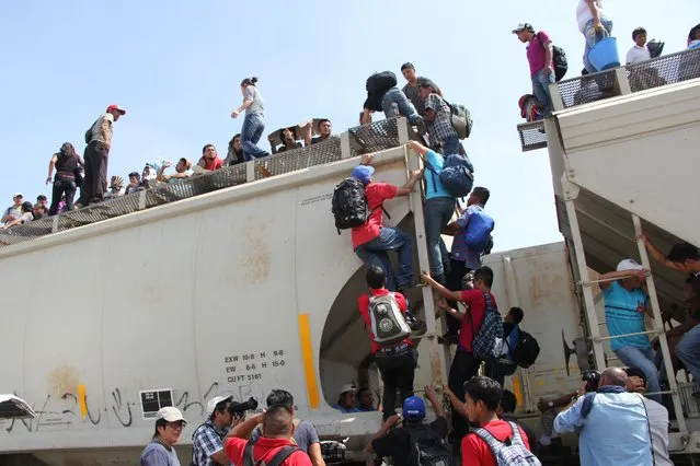 Central American immigrants get on the so-called La Bestia (The Beast) cargo train, in an attempt to reach the Mexico-US border, in Arriaga, Chiapas state, Mexico on July 16, 2014. (Photo by Elizabeth Ruiz/AFP Photo)