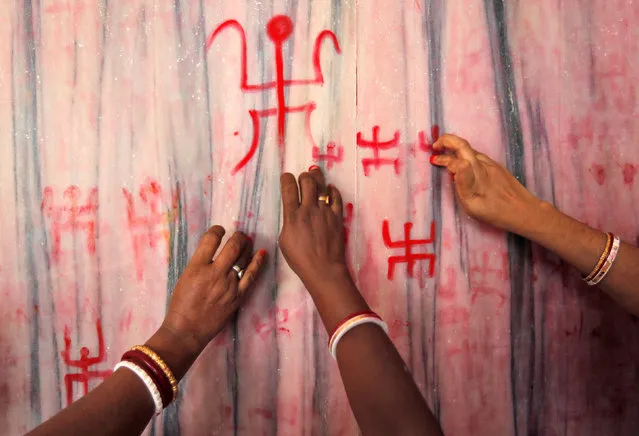 Hindu women paint religious symbols on a wall of a temple on the first day of Ambubachi festival in Agartala, India, June 22, 2016. (Photo by Jayanta Dey/Reuters)