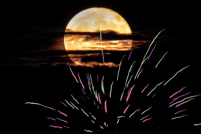 The buck supermoon rises behind fireworks Monday, July 3, 2023, in Kansas City, Mo. The July full moon is the first of four supermoons to rise in 2023. (Photo by Charlie Riedel/AP Photo)