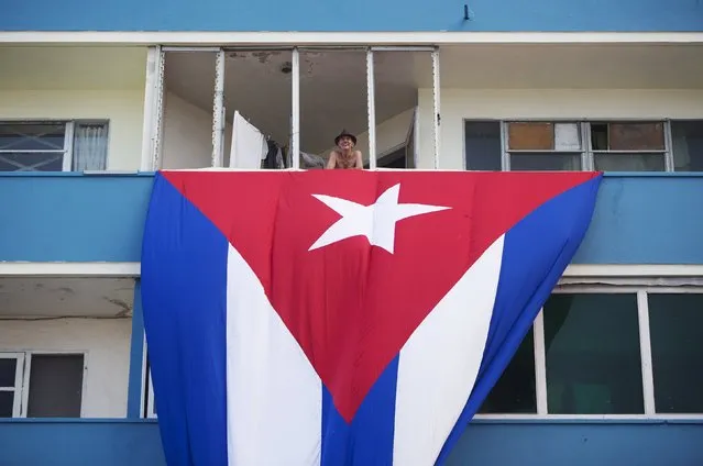 A man stands at his balcony above a Cuban flag, next to the U.S embassy building (not pictured), in Havana, Cuba August 11, 2015. U.S. Secretary of State John Kerry will travel to Cuba on August 14 to formally re-designate the U.S. Interests Section as the U.S. Embassy in Havana. (Photo by Alexandre Meneghini/Reuters)