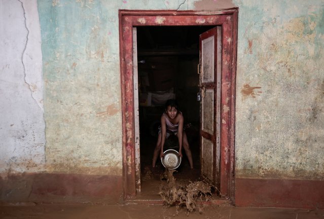 A girl uses a utensil to clear the mud from a house after the flood water recedes following heavy rainfall, along the bank of Kalati River, in Bhumidanda village of Panauti municipality, in Kavre, Nepal on October 1, 2024. (Photo by Navesh Chitrakar/Reuters)