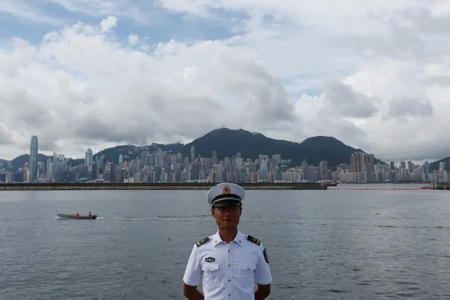 A People's Liberation Army naval soldier stands on a military vessel at a naval base with a Hong Kong skyline at background, during an open day celebrating the 19th anniversary of Hong Kong's handover to Chinese sovereignty from British rule, in Hong Kong July 1, 2016. (Photo by Bobby Yip/Reuters)