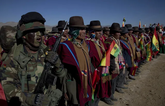 A soldier and Aymara men sing thier national anthem during a military parade commemorating the 192 anniversary of Bolivia's army in Kjasina, Bolivia, Monday, August 7, 2017. (Photo by Juan Karita/AP Photo)
