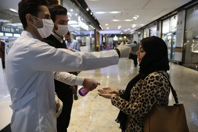 A woman has her temperature checked and her hands disinfected as she enters the Palladium Shopping Center, in northern Tehran, Iran, Tuesday, March 3, 2020. Iran's supreme leader put the Islamic Republic's armed forces on alert Tuesday to assist health officials in combating the outbreak of the new coronavirus, the deadliest outside of China. (Photo by Vahid Salemi/AP Photo)