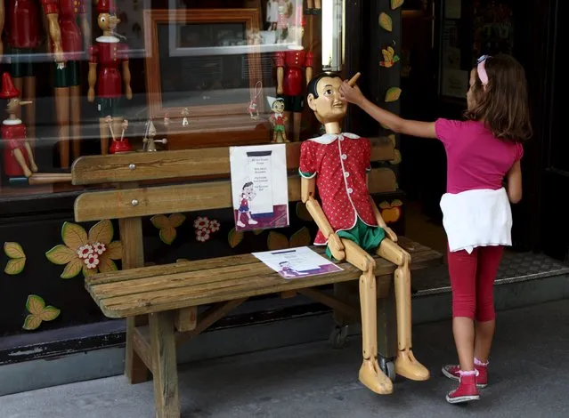A child touches the nose of a Pinocchio puppet, a fictional character of a popular children's novel, at a woodwork souvenir shop in Vienna, Austria, August 21, 2015. (Photo by Heinz-Peter Bader/Reuters)