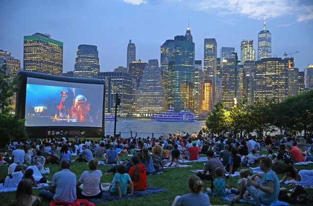 People sit on the grass as they watch Phil Lord and Christopher Miller's The Lego Movie (2014) with skylines of Manhattan's view at Brooklyn Bridge Park in New York, United States on July 27, 2017. “Movies With A View” takes place every Thursday evening in July and August. 340,000 moviegoers, making the program one of New York Citys favorite summer film series. (Photo by Volkan Furuncu/Anadolu Agency/Getty Images)