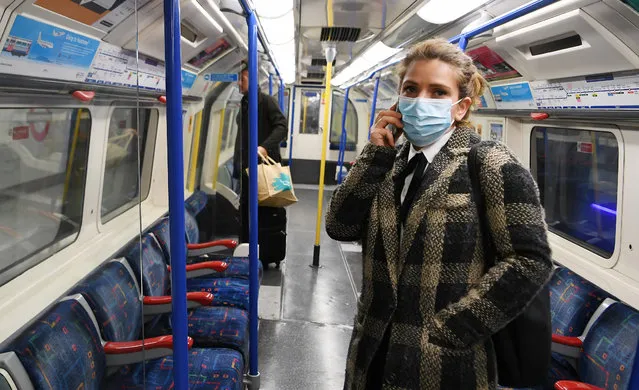 A woman wears a protective mask aboard an Underground train in London, Britain, 14 March 2020. The British government is considering bann​ing mass gatherings due to the Coronavirus. (Photo by Andy Rain/EPA/EFE)