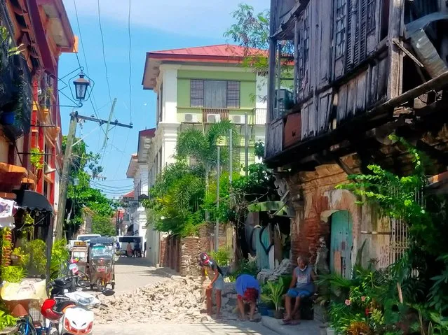 Residents try to clear up debris from an old house in Vigan city, Ilocos Sur province north of Manila on July 27, 2022, after a 7.0-magnitude earthquake hit the northern Philippines, killing one person, shattering windows of buildings at the epicentre and shaking high-rise towers more than 300 kilometres (185 miles) away in the capital Manila. (Photo by Ricardo Raguini/C.J. Ericson Garcia/AFP Photo)
