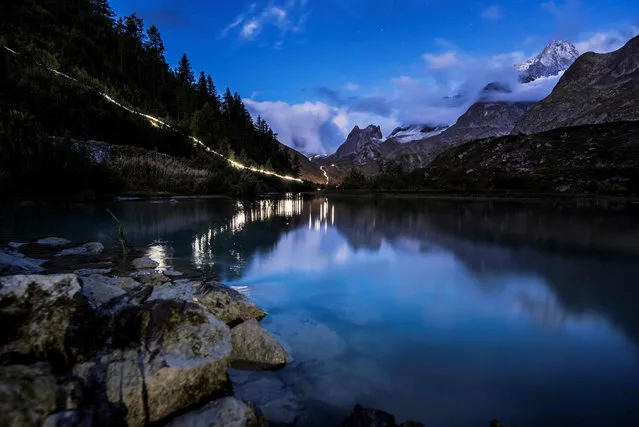 In this long exposure photo, lights of ultra- trailers competing illuminate the way past the Combal lake, on September 2, 2017 in Courmayeur, Italy, during the 15 th edition of the Mount Blanc Ultra Trail (UTMB), a 170 km race around the Mont Blanc crossing France, Italy and Switzerland. (Photo by Jeff Pachoud/AFP Photo)