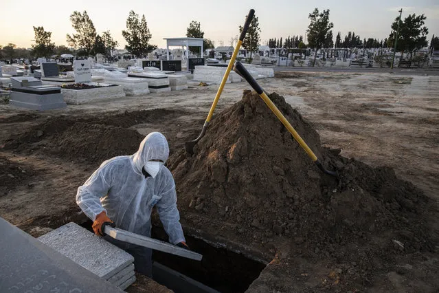 Member of Hevra Kadisha, an organization which prepares bodies of deceased Jews for burial according to Jewish tradition, prepares the grave before a funeral of a Jewish man who died from coronavirus in the costal city of Ashkelon, Israel, Thursday, April 2, 2020. (Photo by Tsafrir Abayov/AP Photo)