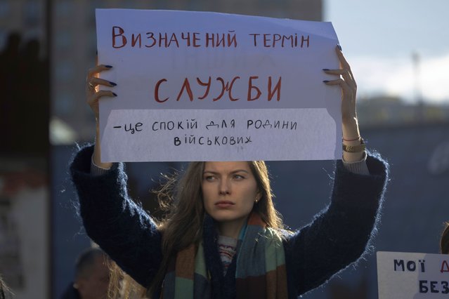 Kateryna Zahidko, who waits for her husband to return from the frontline, holds a poster reading “Defined period of service means calmness for families of soldiers” while attending a meeting in Independence square in Kyiv, Ukraine, Friday, October 27, 2023. Families of Ukrainian servicemen gathered to demand their loved ones return home after serving 18 months in the military as the war with Russia nears its second year. (Photo by Alex Babenko/AP Photo)