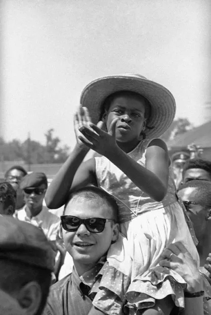 In this June 11, 1966 file photo, a girl claps as she sits on a fellow marcher's shoulder as the Meredith March moves along U.S. 51 near Batesville, Miss. James Meredith started the march from Memphis, Tenn., to Jackson, Miss., to encourage black people to overcome a fear of violence and to encourage them to register to vote. (Photo by AP Photo)