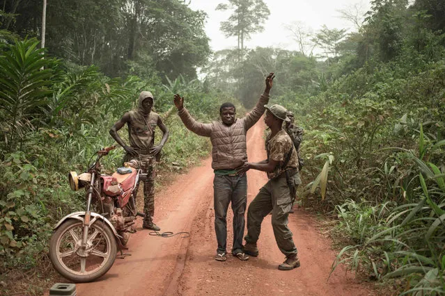 The rangers of the dog squad search a motorcycle taxi for pangolin scales or hunting ammunition in the Dzanga-Sangha Park, in Bayanga, on March 14, 2020. The 4 species of African pangolins are present in the Central African Republic and protected by law since 2019. Poached by the local population, pangolin meat is consumed by hunters and the scales are destined for the Chinese pharmacopoeia market. One jar of pangolin scales sells in Bayanga for about 55 USD. (Photo by Florent Vergnes/AFP Photo)