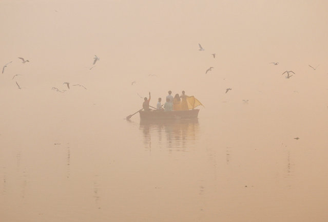 People take pictures on a boat on the Yamuna river on a smoggy morning in New Delhi, India, on November 4, 2024. (Photo by Anushree Fadnavis/Reuters)