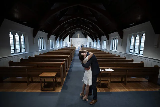 Newly married Tyler and Caryn Suiters embrace following their marriage ceremony performed by Rev. Andrew Merrow in an otherwise empty St. Mary’s Episcopal Church April 18, 2020 in Arlington, Virginia. Rev. Merrow and his wife Cameron Merrow were the only other attendees at the ceremony due to social distancing guidelines implemented in the wake of the COVID-19 pandemic. (Photo by Win McNamee/Getty Images)