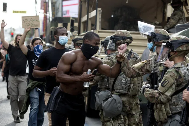 Demonstrators greet members of the National Guard as they march along Hollywood Boulevard, Tuesday, June 2, 2020, in the Hollywood section of Los Angeles, during a protest over the death of George Floyd, who died May 25 after he was restrained by Minneapolis police. (Photo by Ringo H.W. Chiu/AP Photo)