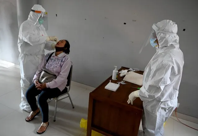 Medical workers wearing protective gear take a sample from a person to be tested for the COVID-19 coronavirus, at a traditional market in Denpasar, Indonesia's resort island of Bali, on June 6, 2020. (Photo by Sonny Tumbelaka/AFP Photo)