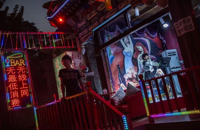 A Chinese woman performs to an empty bar as a server waits for customers on September 18, 2014 in central Beijing, China. (Photo by Kevin Frayer/Getty Images)