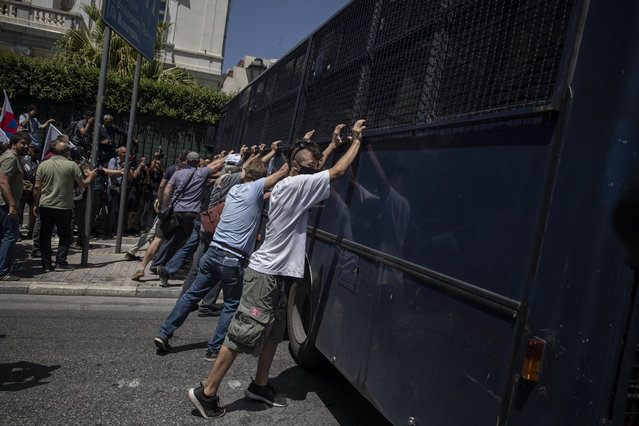 Greek state school teachers try to overturn a a police vehicle blocking the street outside the Greek parliament ,during a protest in central Athens on Tuesday, June 9, 2020. Unions among others oppose government plans to allow remote teaching with use of a camera that will show the blackboard as part of the government's response to the coronavirus pandemic. (Photo by Petros Giannakouris/AP Photo)