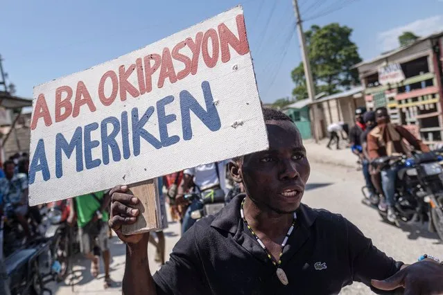 A man holds a placard that reads in Creole “Down with the American Occupation” during a protest demanding the resignation of Haiti's Prime Minister Ariel Henry after weeks of shortages in Port-au-Prince, Haiti on October 17, 2022. (Photo by Ricardo Arduengo/Reuters)