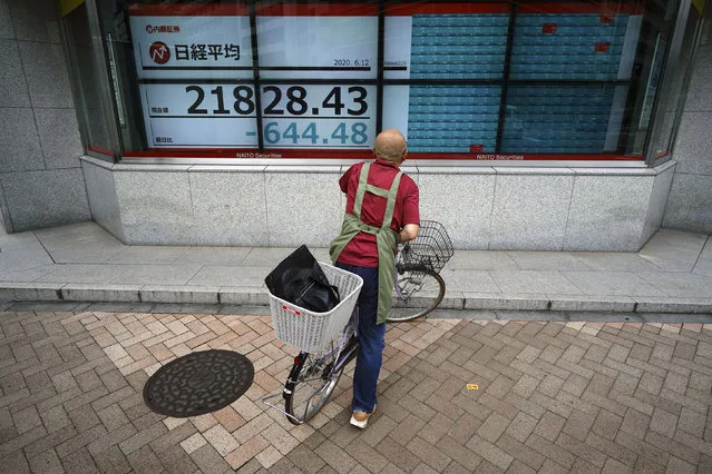 A man on a bicycle looks at an electronic stock board showing Japan's Nikkei 225 index at a securities firm in Tokyo Friday, June 12, 2020. Asian shares were moderately lower Friday after an overnight rout on Wall Street as investors were spooked by reports of rising coronavirus cases in the U.S. (Photo by Eugene Hoshiko/AP Photo)