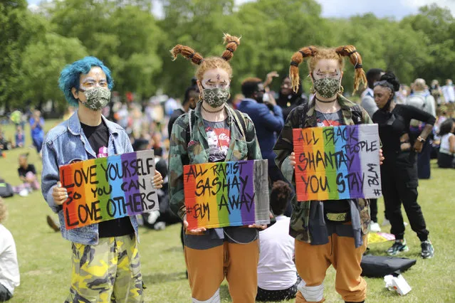 People pose with their slogans during a rally to support the Black Lives Matter cause in central London's Hyde Park, Saturday June 20, 2020. Sign right asks Black people to stay in Britain, and sign centre warns that racists will dance the BLM issue away. (Photo by Aaron Chown/PA Wire via AP Photo)