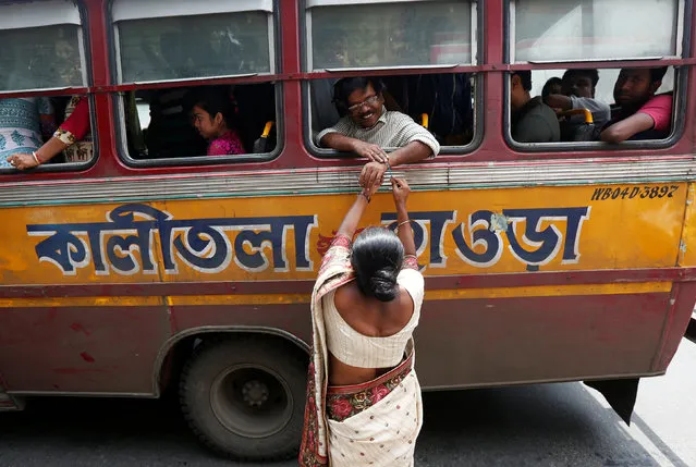 A woman ties “Rakhi” or traditional Indian sacred thread onto the wrists of a man sitting inside a passenger bus during Raksha Bandhan celebrations in Kolkata, India, August 18, 2016. (Photo by Rupak De Chowdhuri/Reuters)