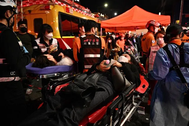 People lie on stretchers to receive medical attention in the popular nightlife district of Itaewon in Seoul on October 30, 2022. Dozens of people suffered from cardiac arrest in the South Korean capital Seoul, after thousands of people crowded into narrow streets in the city's Itaewon neighbourhood to celebrate Halloween, local officials said. (Photo by Anthony Wallace/AFP Photo)