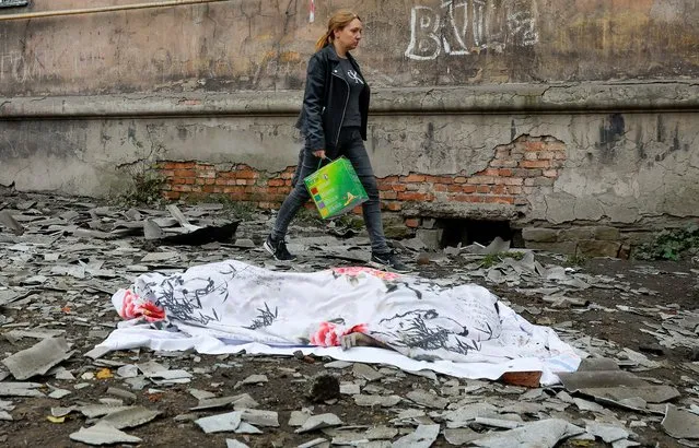 A local resident walks past the body of a person killed by recent shelling near a damaged block of flats in the course of Russia-Ukraine conflict in Makiivka (Makeyevka), Russian-controlled Ukraine on November 4, 2022. (Photo by Alexander Ermochenko/Reuters)