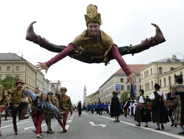 A man dressed as a jester jumps during the traditional costume parade at the Oktoberfest beer festival in Munich, southern Germany, on September 20, 2015. The world biggest Beer festival Oktoberfest will start on September 19, 2015 and take place until October 4, 2015. (Photo by Christof Stache/AFP Photo)