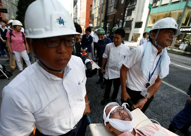 People carry a man role-playing as an injured person on a stretcher in a drill simulating a 7.2 magnitude earthquake in Tokyo, Japan, August 26, 2016. (Photo by Kim Kyung-Hoon/Reuters)