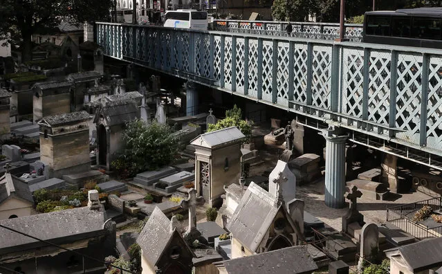 In this Oct. 13, 2014 photo, buses drive on a motorway over the Montmartre cemetery in Paris. Cemetery overcrowding is an issue that resonates around the world, particularly in its most cramped cities and among religions that forbid or discourage cremation. The reality of relying on finite land resources to cope with the endless stream of the dying has brought about creative solutions. (AP Photo/Jacques Brinon)