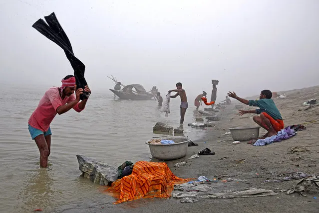 People wash clothes on the banks of the river Brahmaputra on a foggy winter morning in Guwahati, India, December 4, 2017. (Photo by Anuwar Hazarika/Reuters)