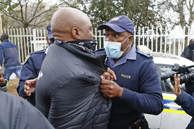 A South African police member grabs a protestor during their picket against the government of Zimbabwe's alleged state corruption, media freedom and the deteriorating economy outside the Zimbabwean Embassy in Pretoria on August 7, 2020. (Photo by Phill Magakoe/AFP Photo)