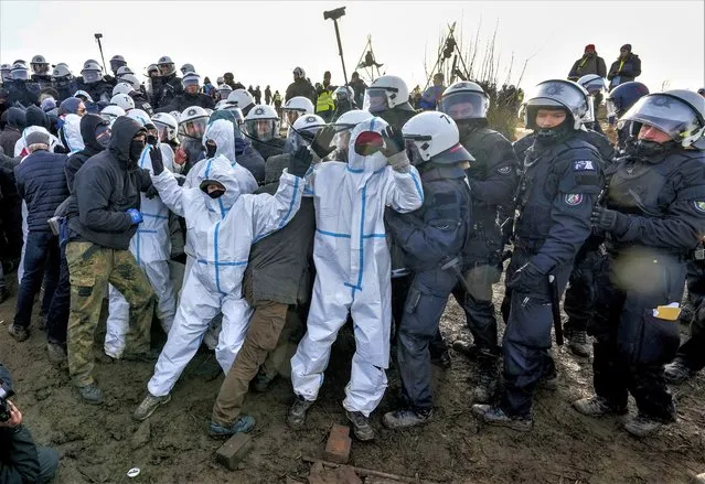 Protesters clash with police officers next to the Garzweiler lignite opencast mine at the Luetzerath village near Erkelenz, Germany, Tuesday, January 10, 2023. Environmental activists were locked in a standoff with police this week around the hamlet of Luetzerath that's due to be bulldozed for the expansion of a nearby lignite mine. (Photo by Michael Probst/AP Photo)