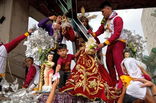 Filipino Catholic devotees wipe their towels at a replica of the Black Nazarene during the feast day, outside Quiapo Church in Manila, Philippines, January 9, 2023. (Photo by Lisa Marie David/Reuters)