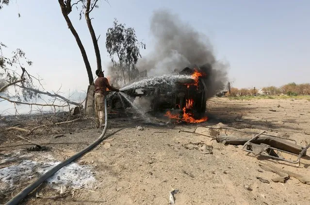A militiaman loyal to Yemen's government extiguishes the fire on a car destroyed in a landmine explosion in Yemen's central province of Marib October 13, 2015. (Photo by Reuters/Stringer)