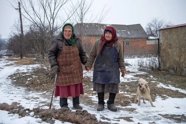 Two friends, Galina, 83, and Valentina, 80, hold hands as they walk along a road, amid Russia's attack on Ukraine, in Siversk, Donetsk region, Ukraine on February 18, 2023. (Photo by Marko Djurica/Reuters)