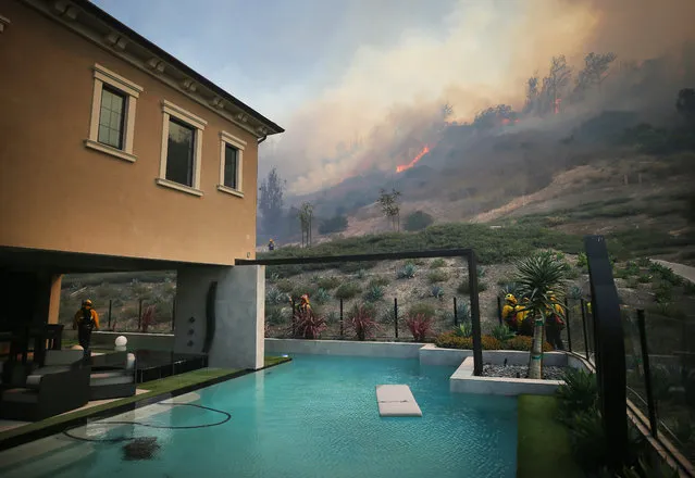 Firefighters work as the Silverado Fire burns toward a home in Orange County on October 26, 2020 in Irvine, California. The fire has prompted mandatory evacuations of 60,000 residents and has grown to 4,000 acres. (Photo by Mario Tama/Getty Images)