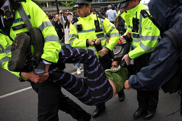 Metropolitan Police officers (MET) arrest protesters taking part in a gathering around a bus reportedly waiting to remove migrants and asylum seekers from a hotel in Peckham, south London, as they block it from transporting them to the Bibby Stockholm barge in Portland, Dorset, south-west England, on May 2, 2024. Protesters in London tried Thursday to prevent the removal of migrants from their temporary accommodation, as the UK government began detaining people before controversial deportation flights to Rwanda start. (Photo by Henry Nicholls/AFP Photo)