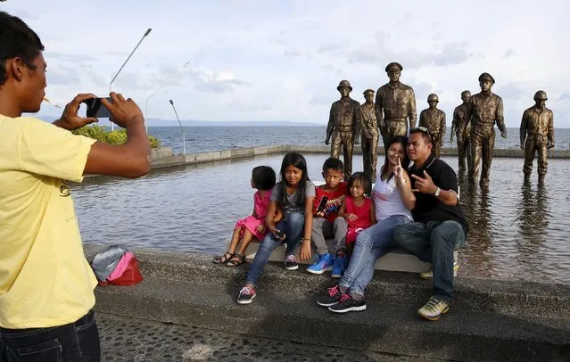 Residents pose in front of the bronze images of U.S. General Douglas McArthur and his officers at a memorial in Palo, Leyte in central Philippines November 2, 2015, ahead of the second anniversary of a devastating typhoon that killed more than 6,000 people in central Philippines. (Photo by Erik De Castro/Reuters)