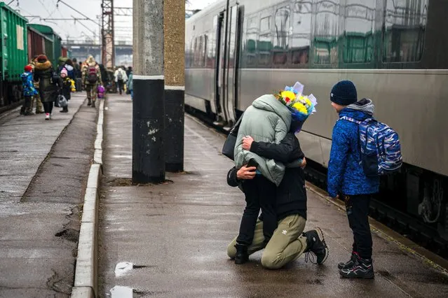 A Ukrainian man falls to his knees as he welcomes his family upon their arrival from Kyiv at the train station in Kramatorsk on February 26, 2023, amid the Russian invasion of Ukraine. (Photo by Dimitar Dilkoff/AFP Photo)