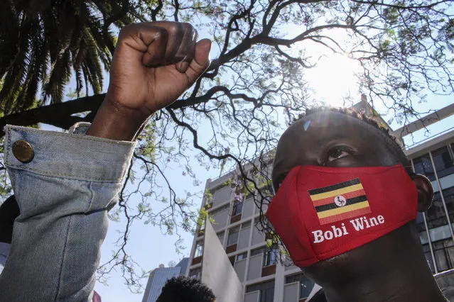 A Ugandan supporter of opposition presidential candidate Bobi Wine, wearing a face mask with the Ugandan national flag, joins others to protest his arrest and call for his release and an end to police brutality, outside the Ugandan High Commission in Nairobi, Kenya Thursday, November 19, 2020. (Photo by AP Photo/Stringer)