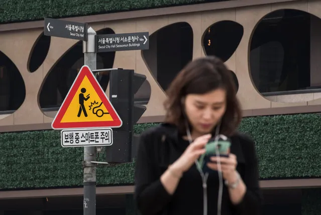 A sign advising pedestrians of the dangers of using smartphones while walking is displayed at an intersection in central Seoul on June 22, 2016. Officials in Seoul, the most wired city in the world, have launched a pilot campaign hoping fresh warning signs will help keep pedestrians off their smartphones on the streets. (Photo by Ed Jones/AFP Photo)