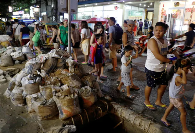 People walk past a clogged sewer and uncollected sacks containing waste from the sewers along a road at Boracay in Philippines April 9, 2018. (Photo by Erik De Castro/Reuters)